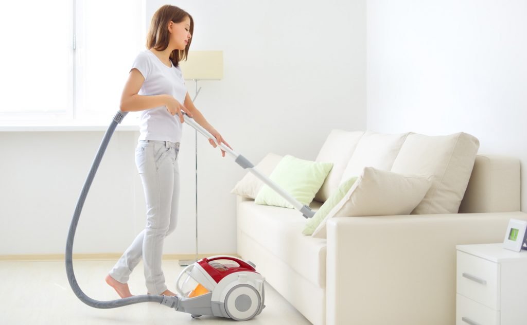 Lady cleaning cushion covers with vacuum cleaner