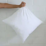 A hand is holding out a cushion insert 45x45 cm size.