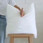 A hand is chopping a 45x45 cushion insert to show how it retains its shape.