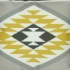 Close up of yellow, grey and white velvet cushion with Aztec print