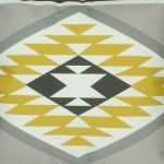 Close up of yellow, grey and white velvet cushion with Aztec print