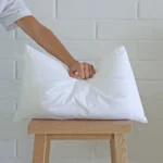 A hand is pressing a 30x50 cushion insert to show its quality and durability.