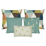 A collection of five cushions with in teal, gold, white, brown and grey colours with pine, triangle and cross designs