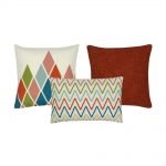 A collection of 3 cushion covers with burnt orange and white colours and in zigzag and diamond patterns.