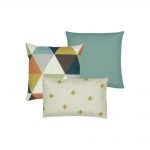 A collection of three cushion covers in teal, gold, grey, orange and brown colours with color blocked, cross and triangle designs