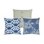 A collection of 3 square blue and white cushion covers in shell, floral and cable knit patterns