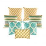 A set of 7 cushion covers with diamond and, zigzag and crown patterns in gold and teal colours