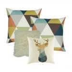 A collection of four cushion covers in teal, gold and white colours in triangle and moose design