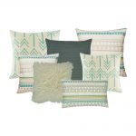 A collection of seven cushions in teal, grey and white colours with arrow designs