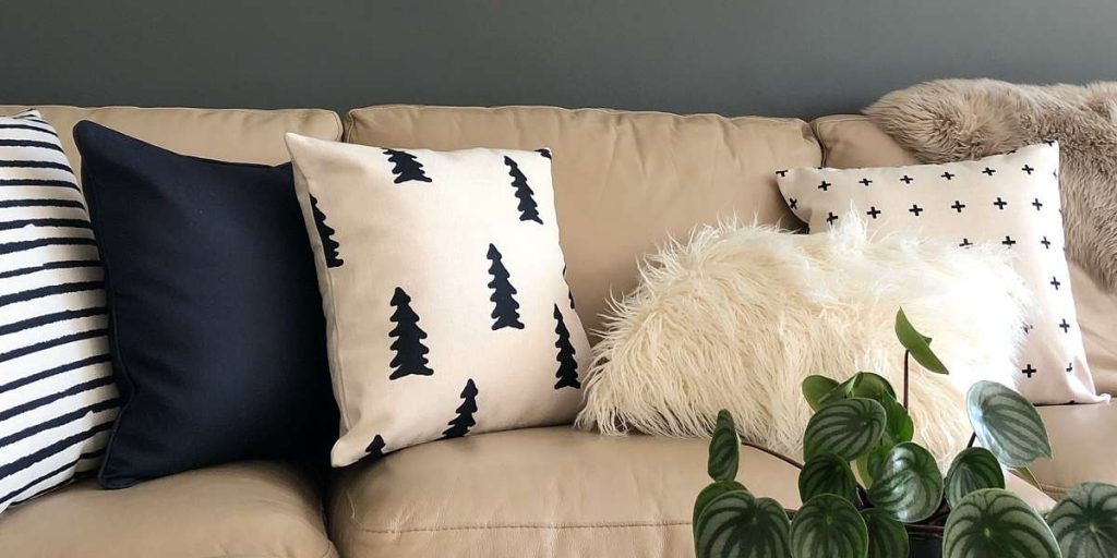 Cream sofa with a very dark navy cushion surrounded by black and white varieties including a faux fur cushion cover