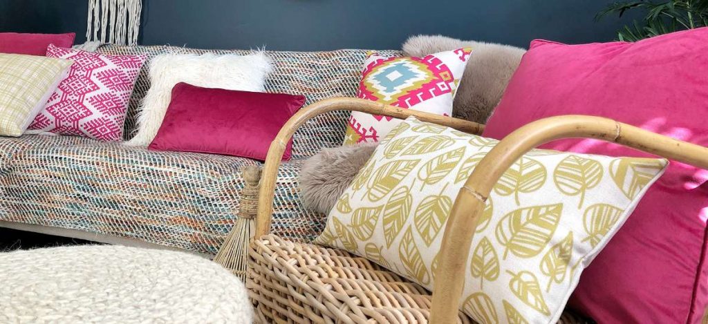 A living room styled with Boho chic style decor with pink and yellow cushions