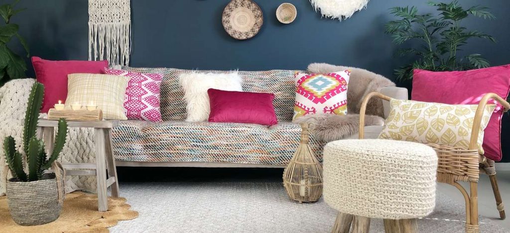 A boho chic styled room with pink, cream and yellow cushions with eclectic decor and furnishings