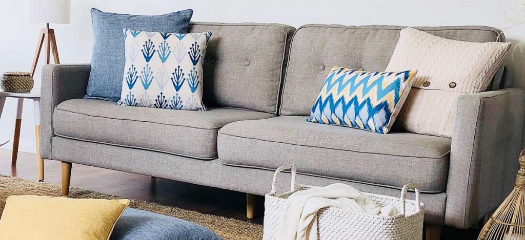 A coastal styled scene with blue and beige cushions on a grey sofa