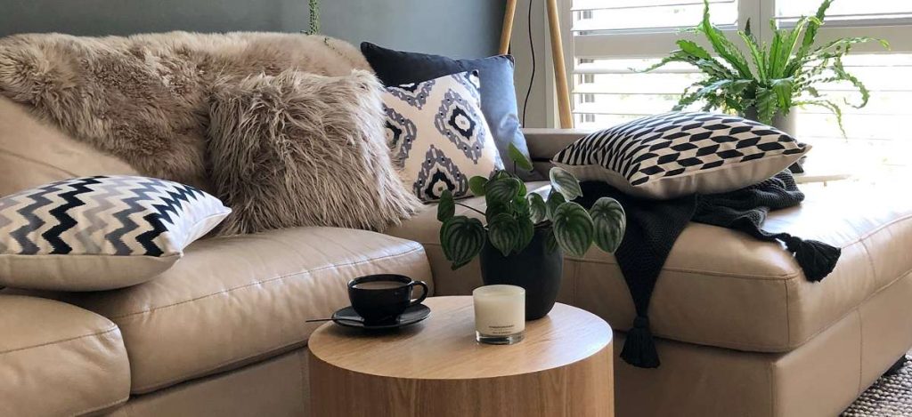 Sofa scene with 5 cushions layered on a cream sofa