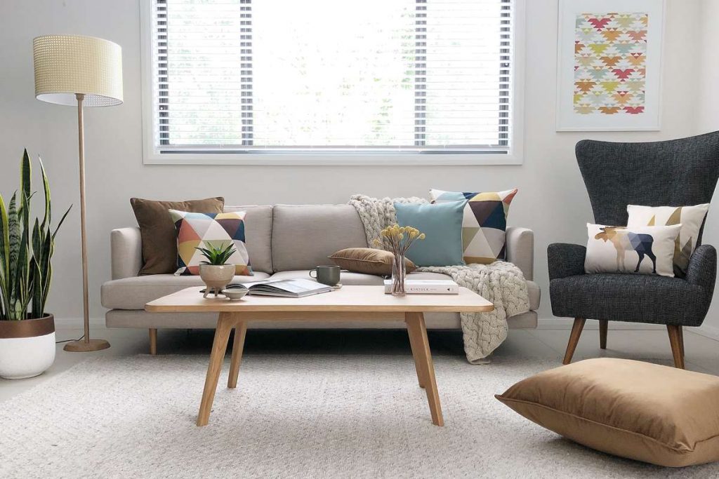 A living room scene styled out with mid-century modern themed decor including a large collection of brown and autumn coloured cushions