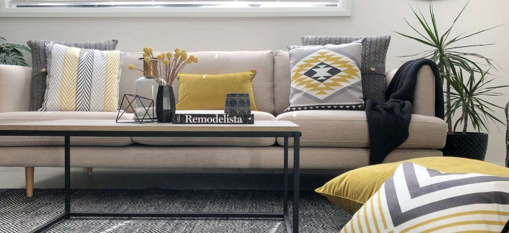 Living room fitted out with urban modern decor including mustard coloured cushions, a navy throw rug and and black table yellow chevron designs