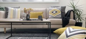 Living room fitted out with urban modern decor including mustard coloured cushions, a navy throw rug and and black table yellow chevron designs