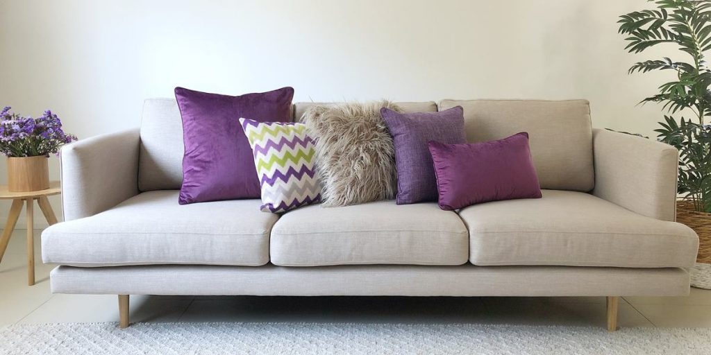 A grey sofa with 5 cushions in all different textures