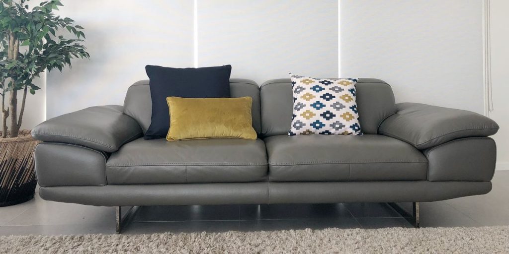 Lounge room with a grey sofa that has a large dark blue cushion in the background and a mustard and navy print cushion in the foreground