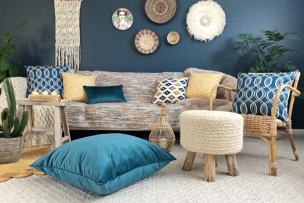 Large blue floor pillows sit in the front of a scene decorated with a boho look