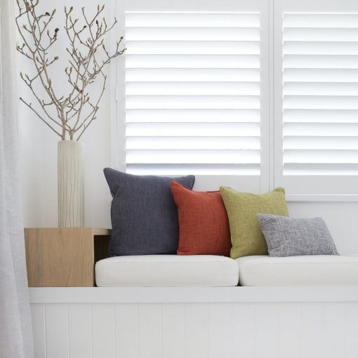 A series of Arlington cushions are shown in grey, red, green and light grey. They sit on a white day bed.