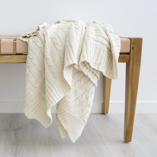 Beige throw blanket positioned on end of a pink chair