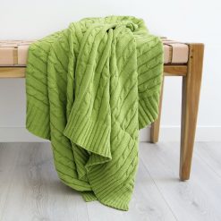 Vibrant green throw blanket with a fine cotton weave folded over a chair