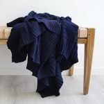 Beautiful navy throw blanket artfully arranged on top of a seat