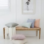 A collection of panama cushions styled on a wooden chair. There are rectangles and square shapes in soft pastel tones.