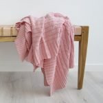 Beautiful pink throw blanket layered on a wooden bench