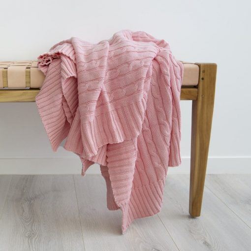 Beautiful pink throw blanket layered on a wooden bench