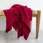 Bright red throw blanket and rug folded to show a rich texture over a bench seat