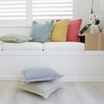 Sandblasted cotton cushions sit on a light day bed. The bright pink, yellow, blue and green tones look vibrant.