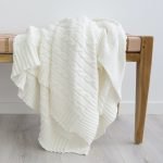 Folded white throw blanket laying on a wooden bench seat