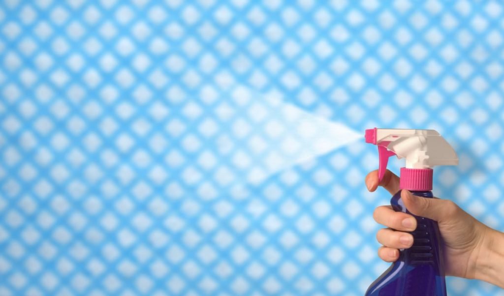 A hand sprays a deodorising product through the air