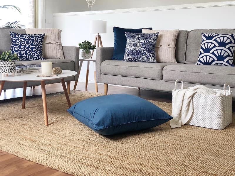 A coastal themed room is shown with blue large outdoor floor cushions positioned near the exit to an outdoor area