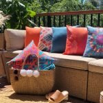 A bright collection of orange and blue outdoor cushions styled on a light coloured sofa