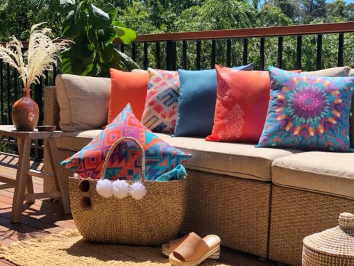 A bright collection of orange and blue outdoor cushions styled on a light coloured sofa