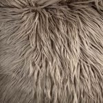 Close up of light tawny brown square cushion cover in fur fabric
