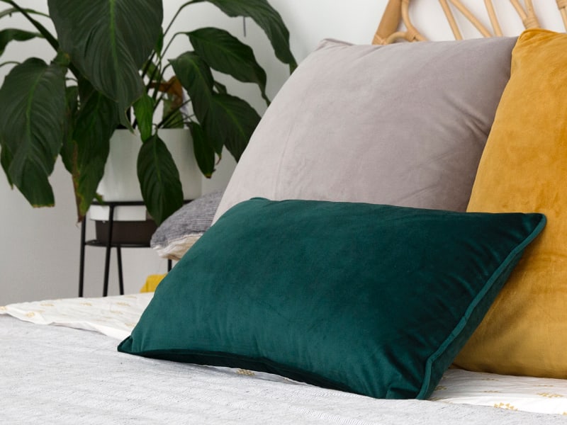 Emerald green cushions arranged on a stylish queen bed with a neutral bed cover
