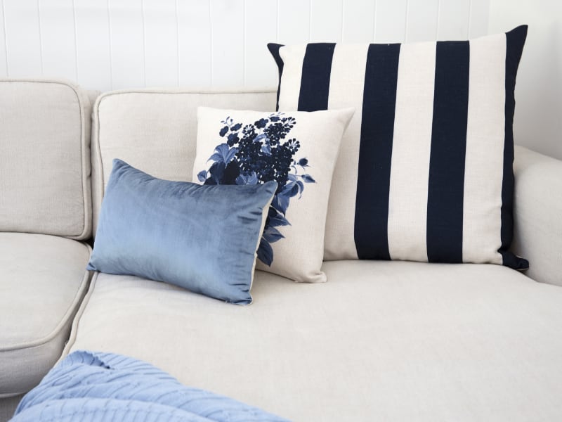 Blue big cushions arranged tastefully in front of one another on a beige coloured couch