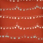 Close up photo of red Christmas cushion with a string of baubles