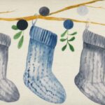 Close up photo of minimalist rectangular cushion cover with socks and mistletoe