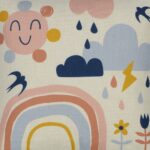 Close up photo of pastel coloured kids cushion cover with rainbow, sun, flowers and clouds