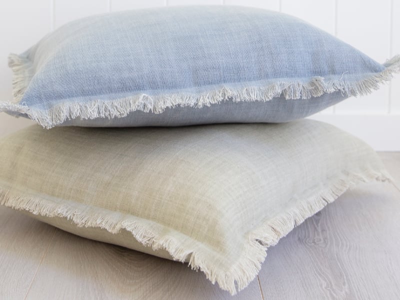 A stack of sage cushions is shown with each featuring a soft frilled edge