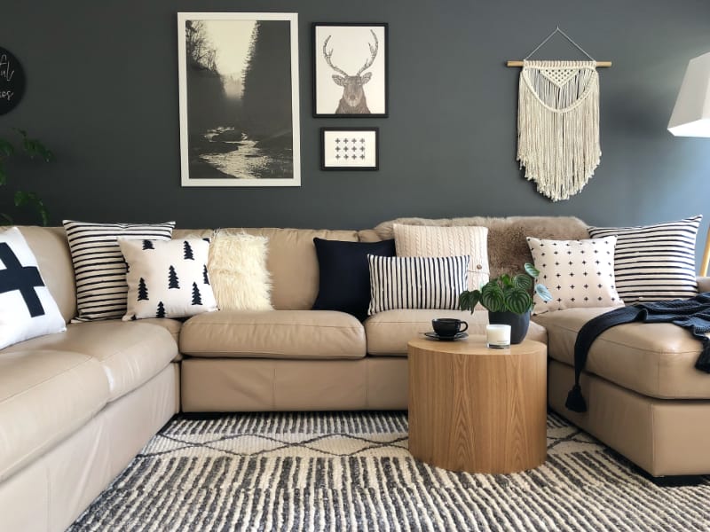 Black and white cushion covers arranged on a beige sofa with monochrome wall art and hangings on the wall