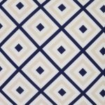 A close up view of a striking geometric pattern is shown on a beige navy outdoor cushion cover.