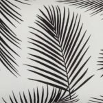 A close up view of a rectangular black and white outdoor cushion with beautiful palm leaf pattern on both sides.
