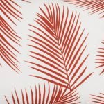 A close up view of a rectangular red outdoor cushion with beautiful palm leaf pattern on both sides.