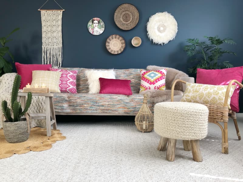 Here a Bohemian inspired living room is shown with an eclectic mix of ornaments and decor surrounding a course couch that features a selection of boho cushions and sits on a light coloured rug